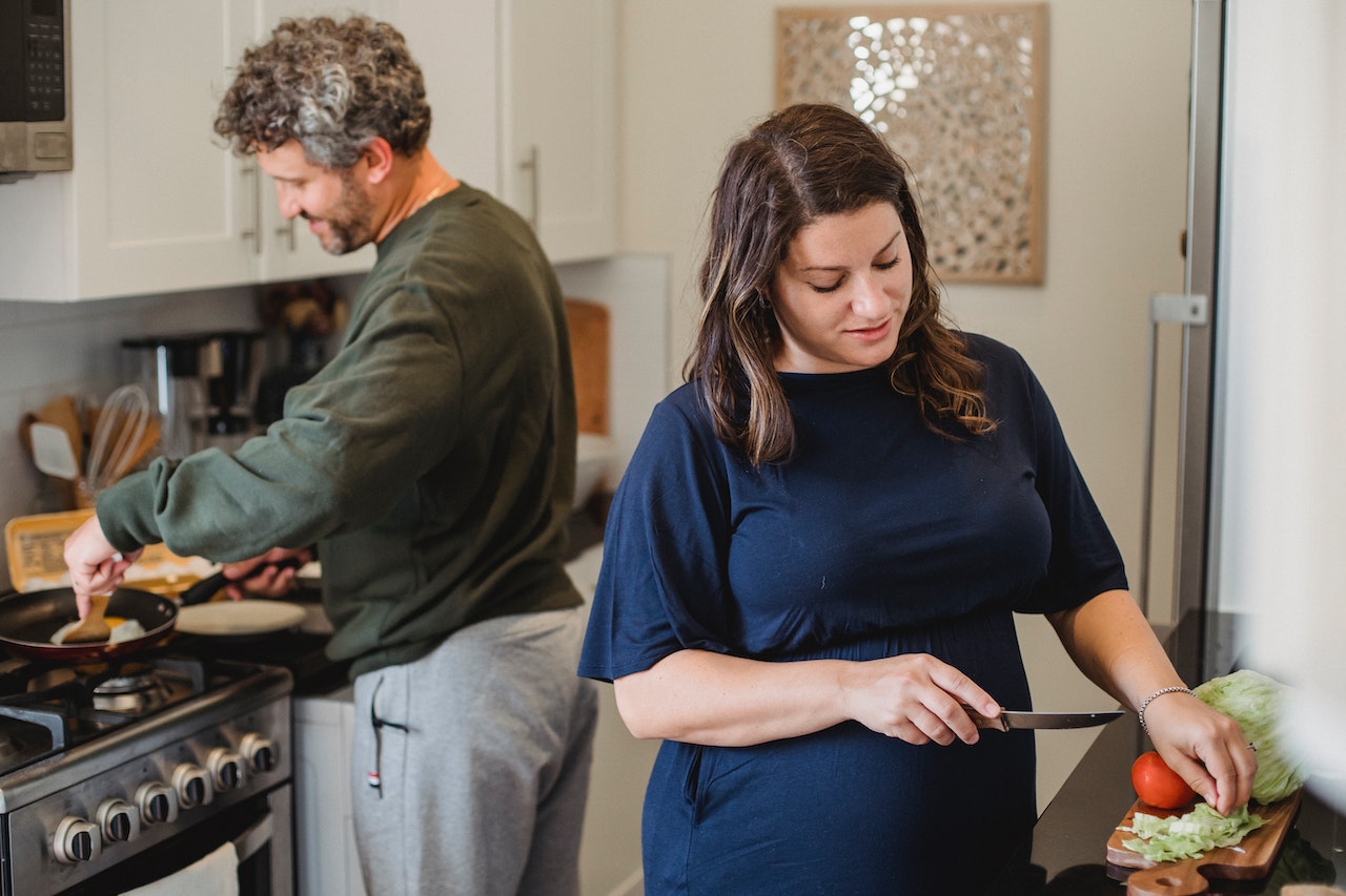 kobieta w ciąży z partnerem przygotowują jedzenie